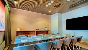 A conference room with a long table, chairs, a projector screen, and a wooden ceiling. - Scandic Veromies (Vantaa)