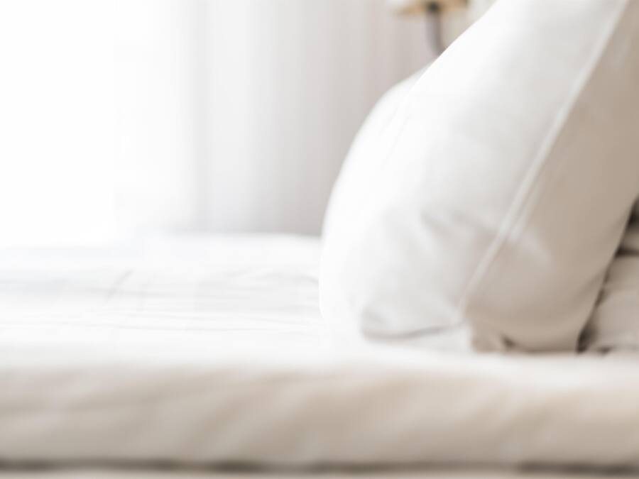 Una cama con ropa blanca y una almohada.