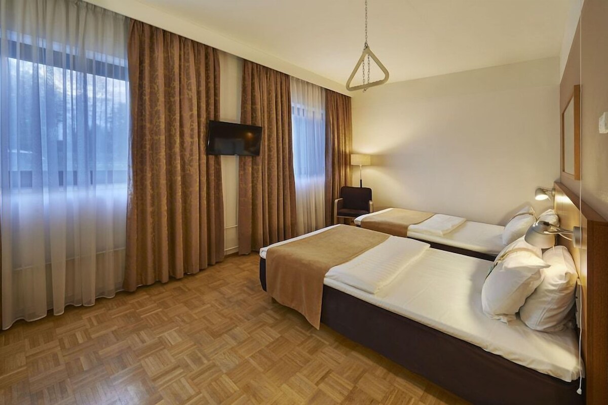 A hotel room with two beds, a television, a desk, and a chair.