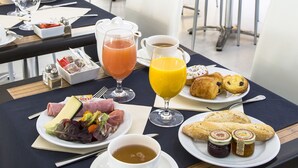 A breakfast setting with a table set for two, featuring a variety of food items, a glass of orange juice, and a cup of coffee. - CRISTAL HOTEL & SPA (Cannes)