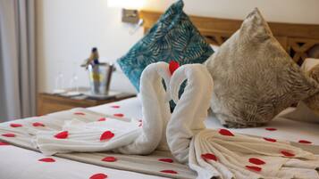 A bed with two white towels arranged in a swan shape, a teal pillow, and a wooden headboard.