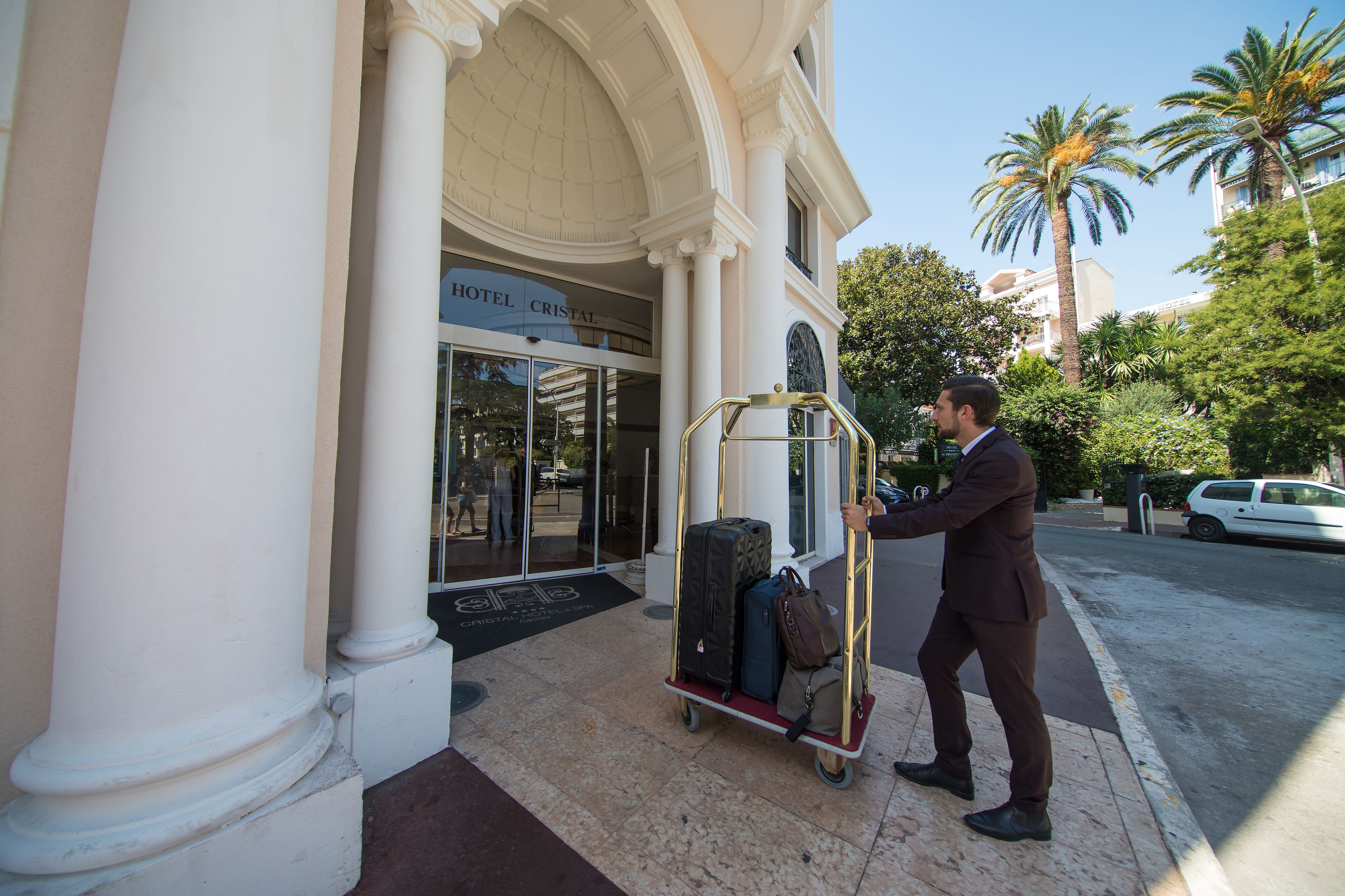 A man with luggage at the entrance of a hotel named "HOTEL CRISTAL".