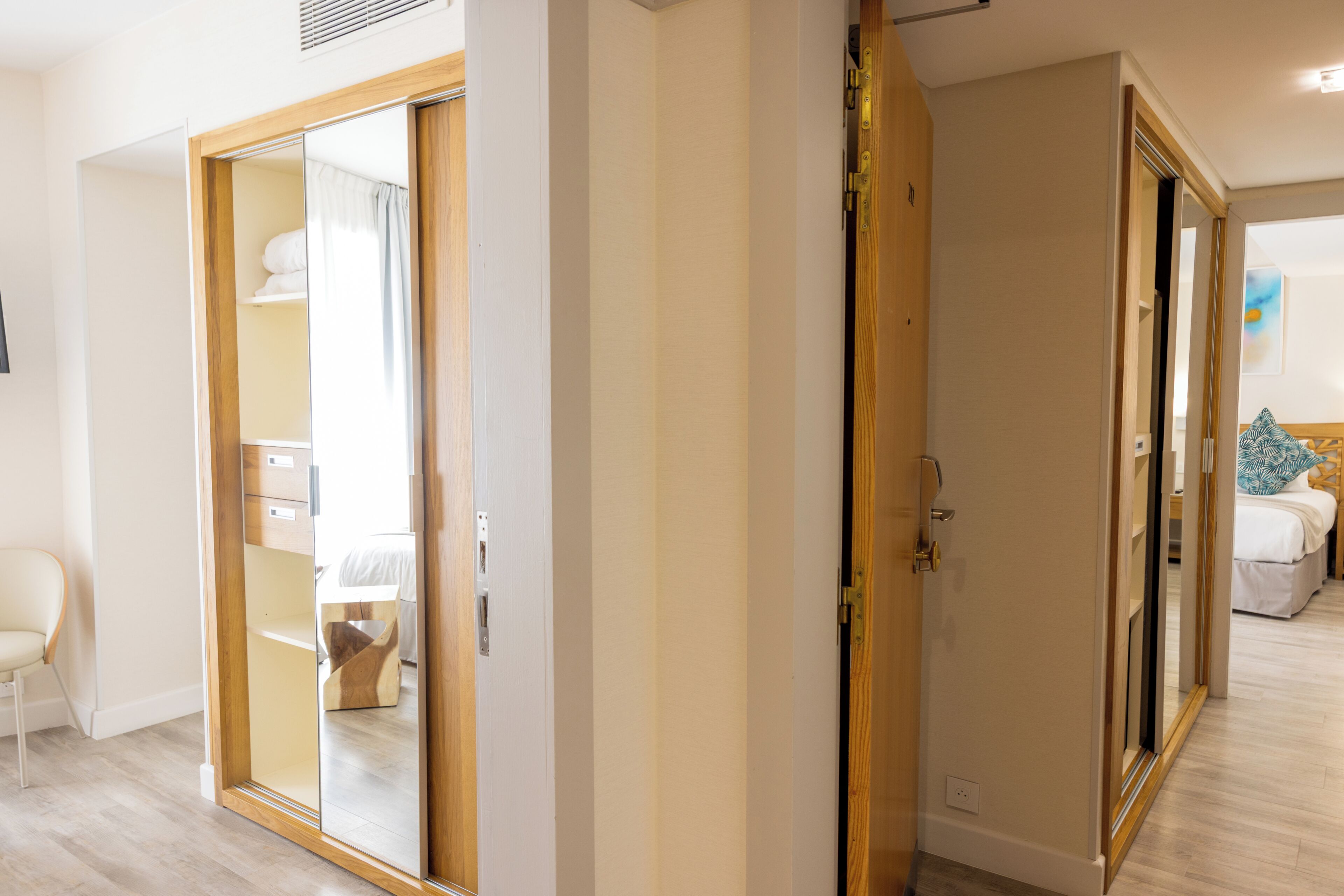 Una habitación con puerta corrediza de vidrio que da a un baño, una cama con cabecera azul y una silla blanca.