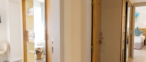 Una habitación con puerta corrediza de vidrio que da a un baño, una cama con cabecera azul y una silla blanca.