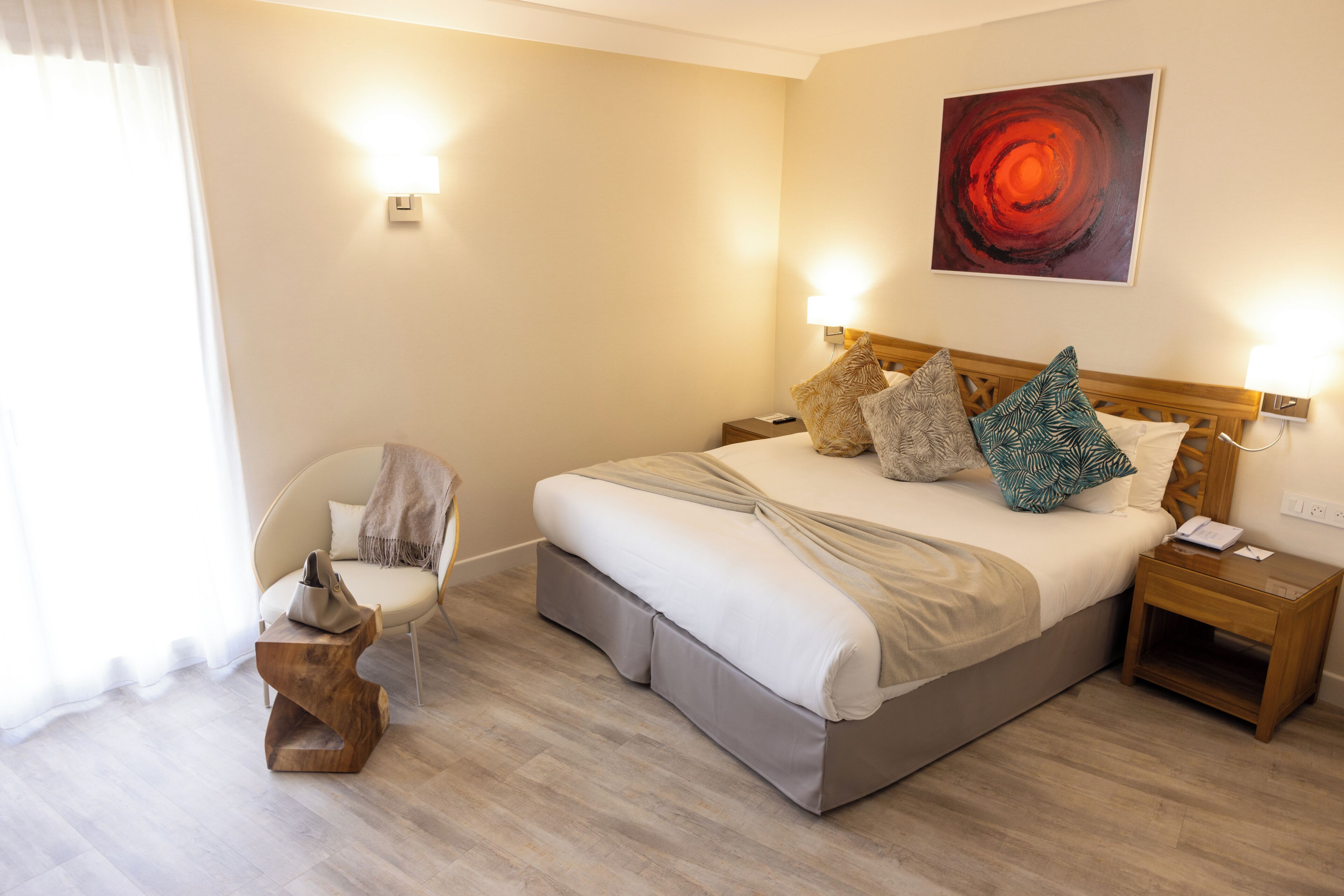 Une chambre d’hôtel avec un lit, une chaise, une table de chevet et une œuvre d’art accrochée au mur.
