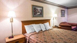 Habitación de hotel con cama, dos lámparas de noche, mesita de noche con un reloj, teléfono y una silla.