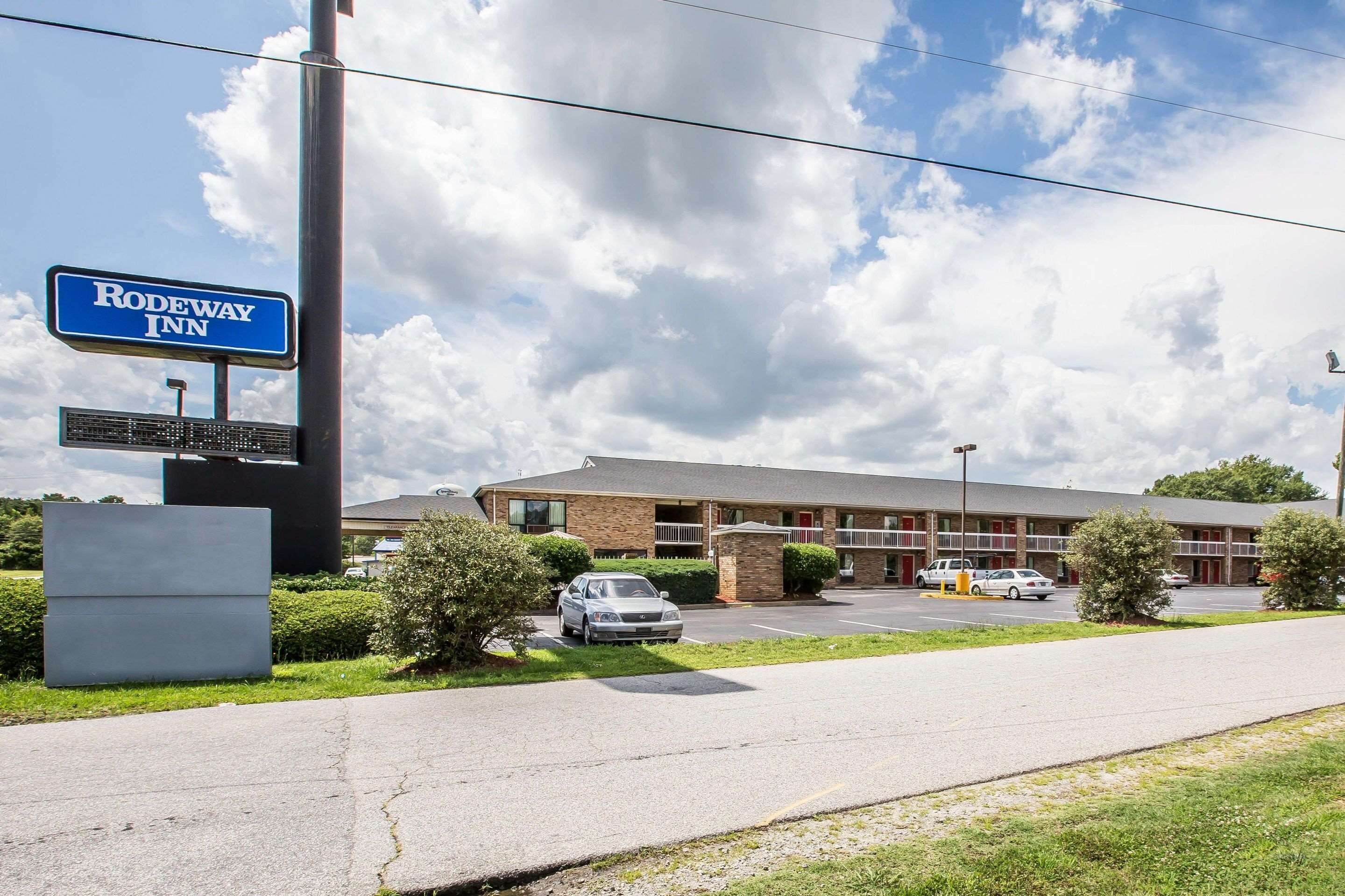 A Rodeway Inn with a brick building, a parking lot, and a clear sky.