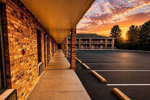 A building with a brick facade, a covered walkway, and a parking lot. - Rodeway Inn Expo Center (Spartanburg)