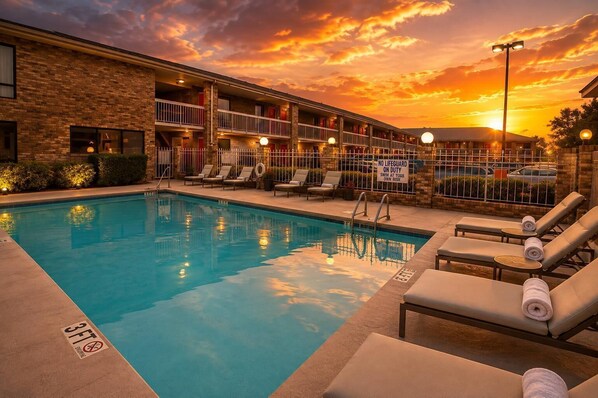 A swimming pool with lounge chairs and a sign indicating no lifeguard on duty.