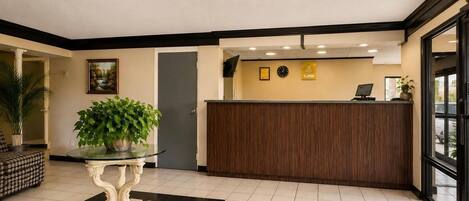 A reception area with a reception desk, a clock, and a potted plant.