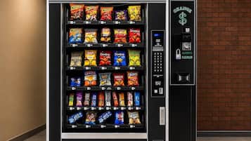 A vending machine with a variety of snack options, including chips and candies, and a digital payment interface.