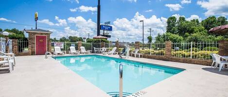 A swimming pool with lounge chairs, a lifeguard tower, and a sign for Rodeway Inn.
