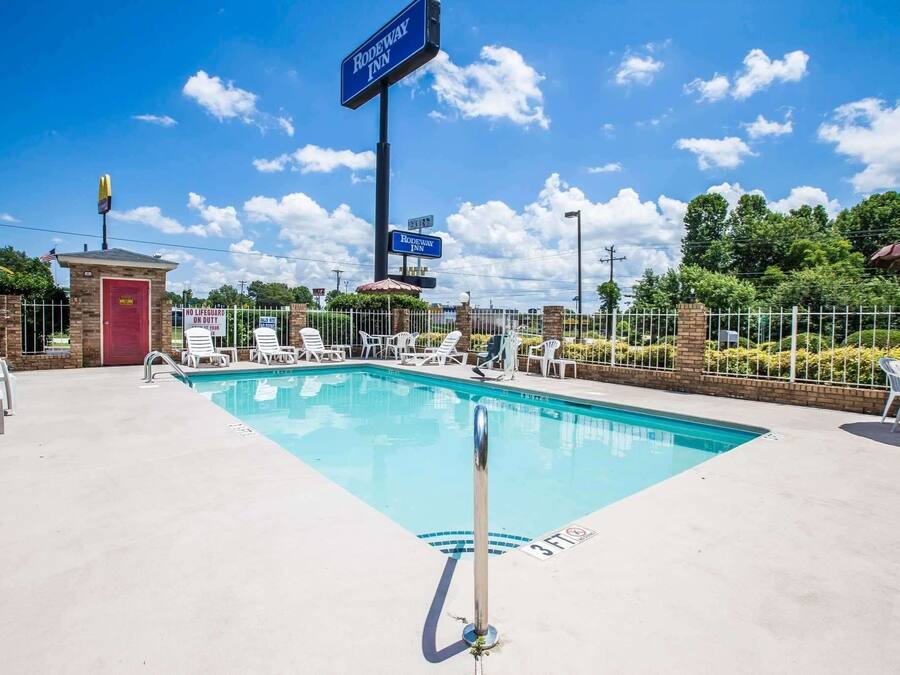 A swimming pool with lounge chairs, a lifeguard tower, and a sign for Rodeway Inn.