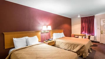 A hotel room with two beds, a desk, a chair, and a window with curtains.