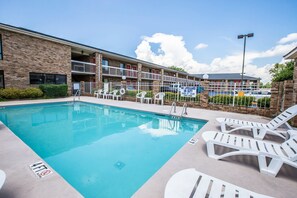 Une piscine avec des chaises longues et un panneau indiquant la présence d’un sauveteur.