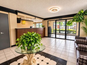 A reception area with a glass-top table, a reception desk, a refrigerator, and a sofa.