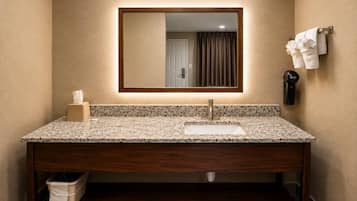 A bathroom with a large mirror, a sink, a towel rack, and a trash bin.