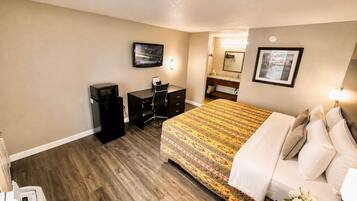 Quarto de hotel com cama, escrivaninha e televisão.
