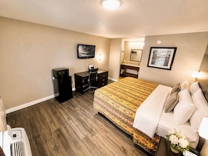 Una habitación de hotel con cama, escritorio y televisión.