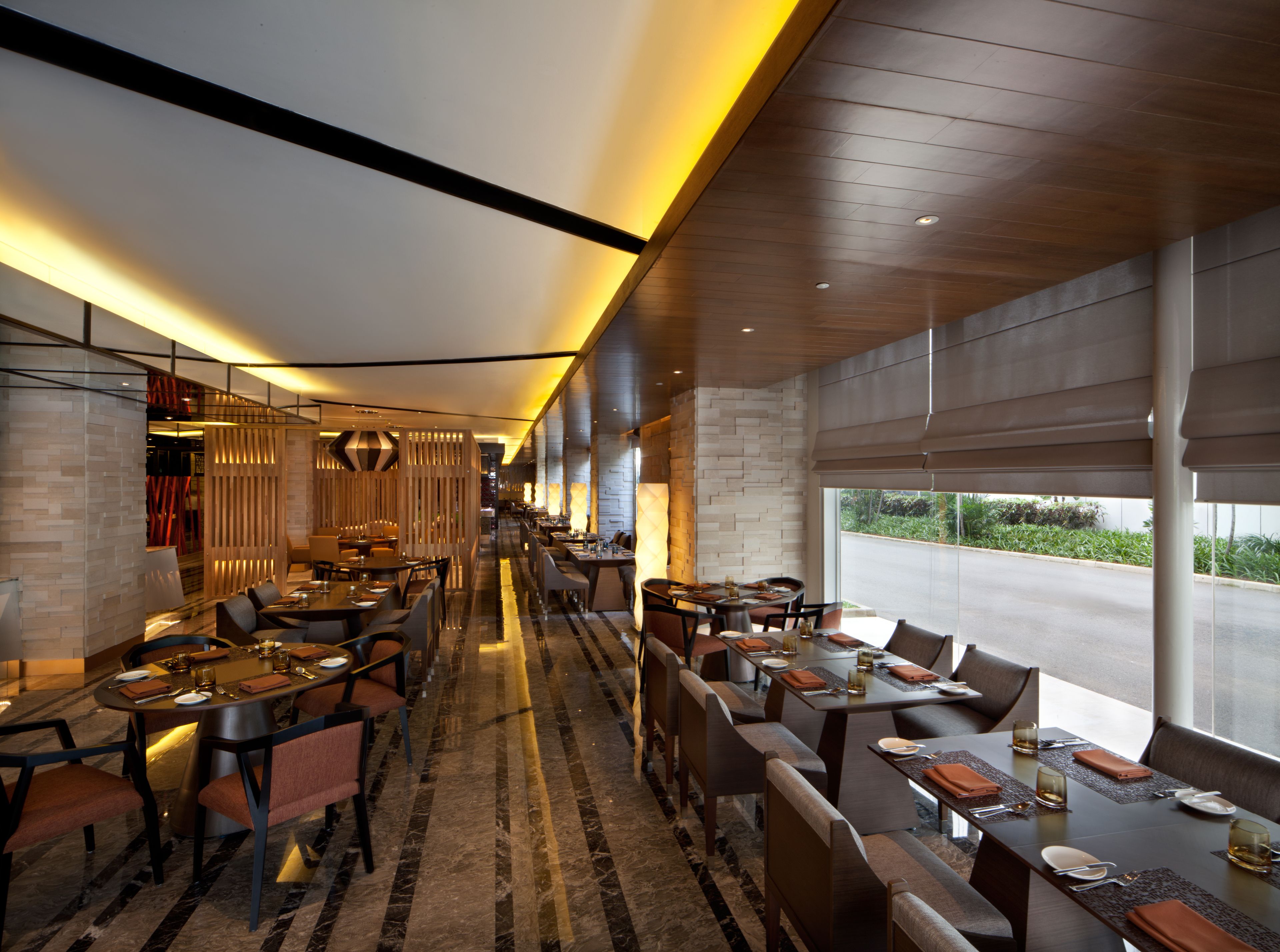 Un restaurante moderno con mesas largas y cabinas, un suelo estampado y vistas al exterior.