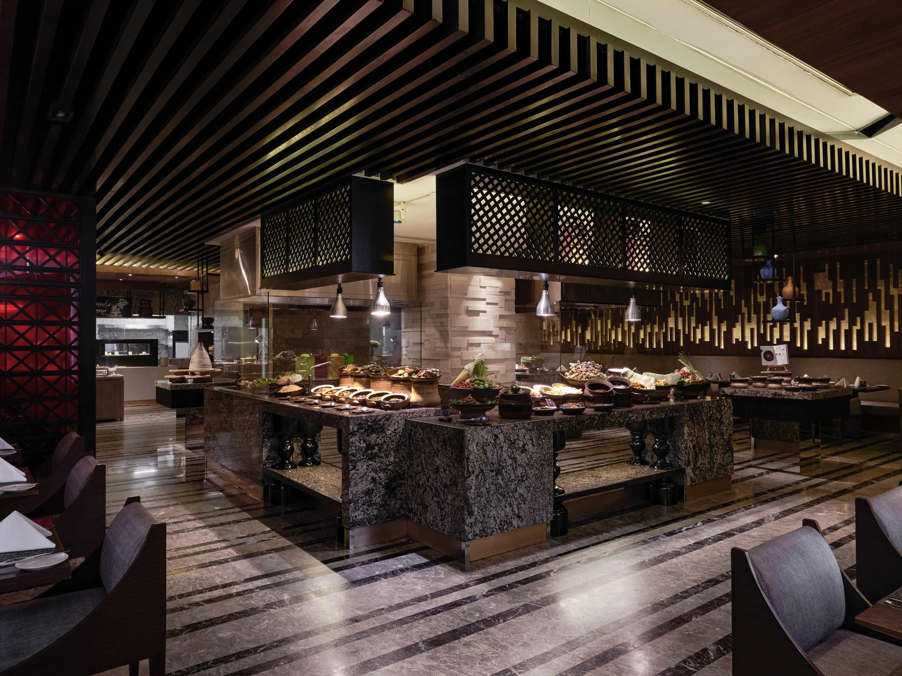 A modern restaurant with a central island, seating area, and a decorative ceiling.