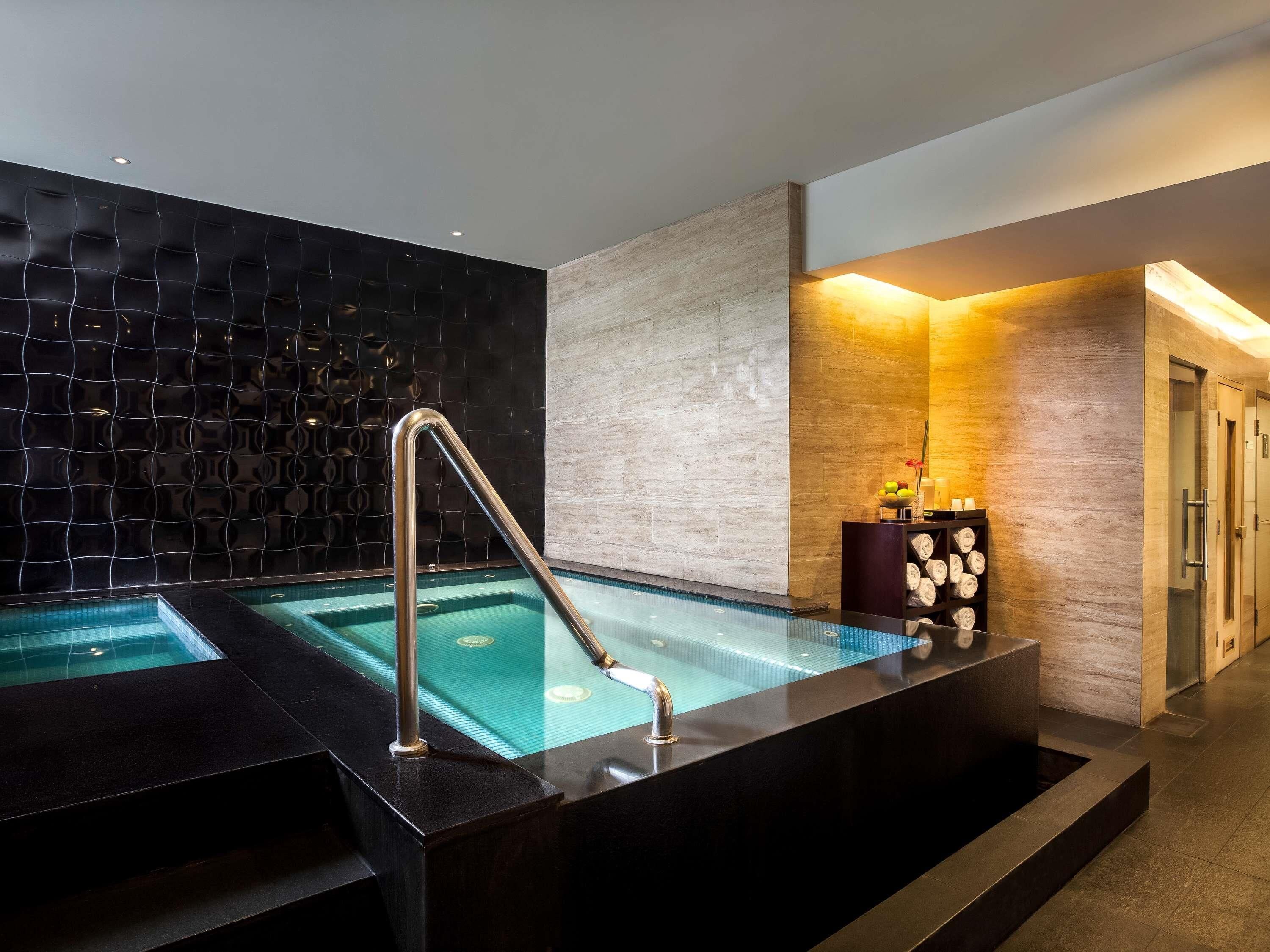 A spa area with a hot tub, a towel rack, and a wall with a textured pattern.