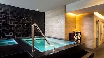 A spa area with a hot tub, a towel rack, and a wall with a textured pattern.