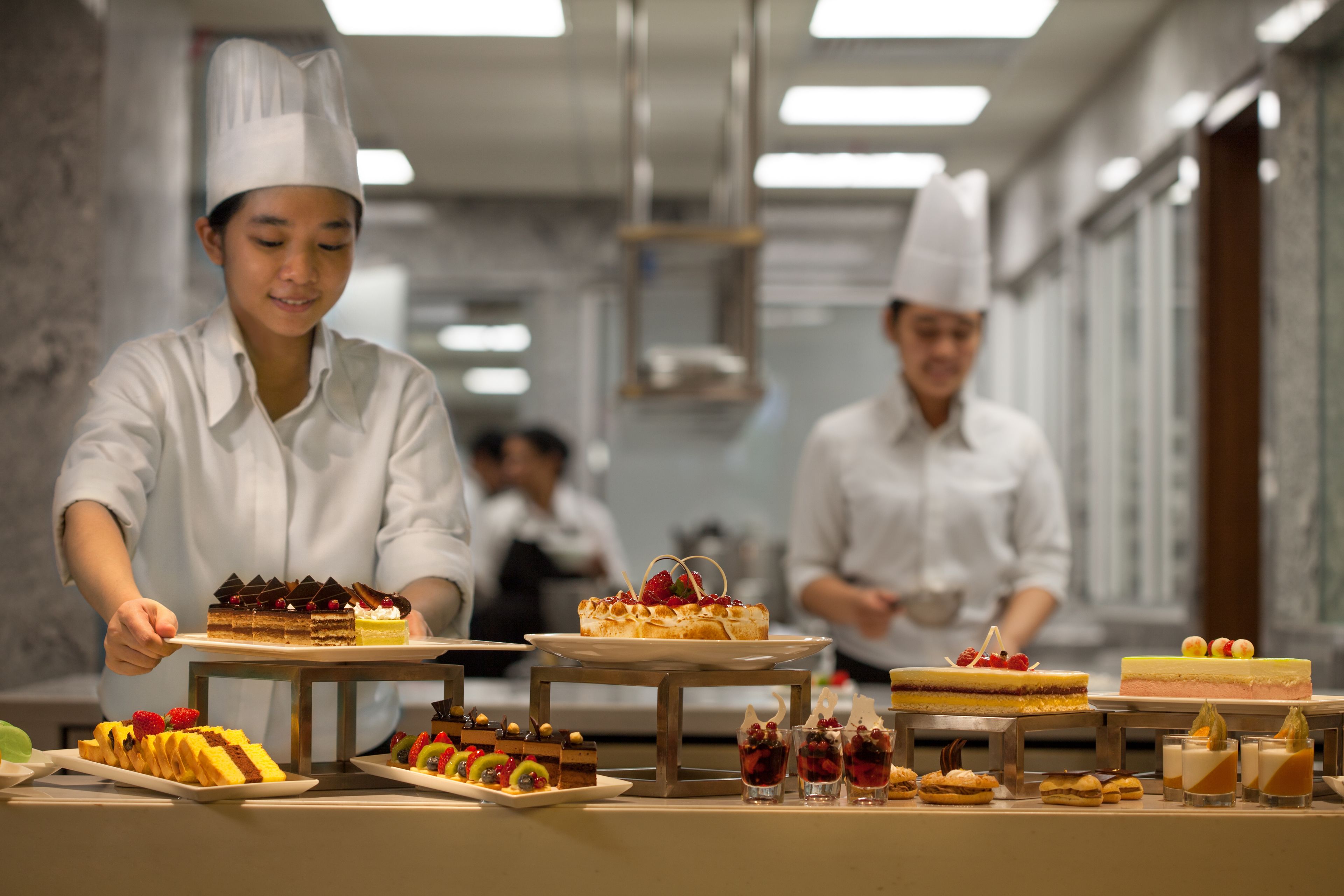 Une cuisine professionnelle où des chefs préparent des desserts.