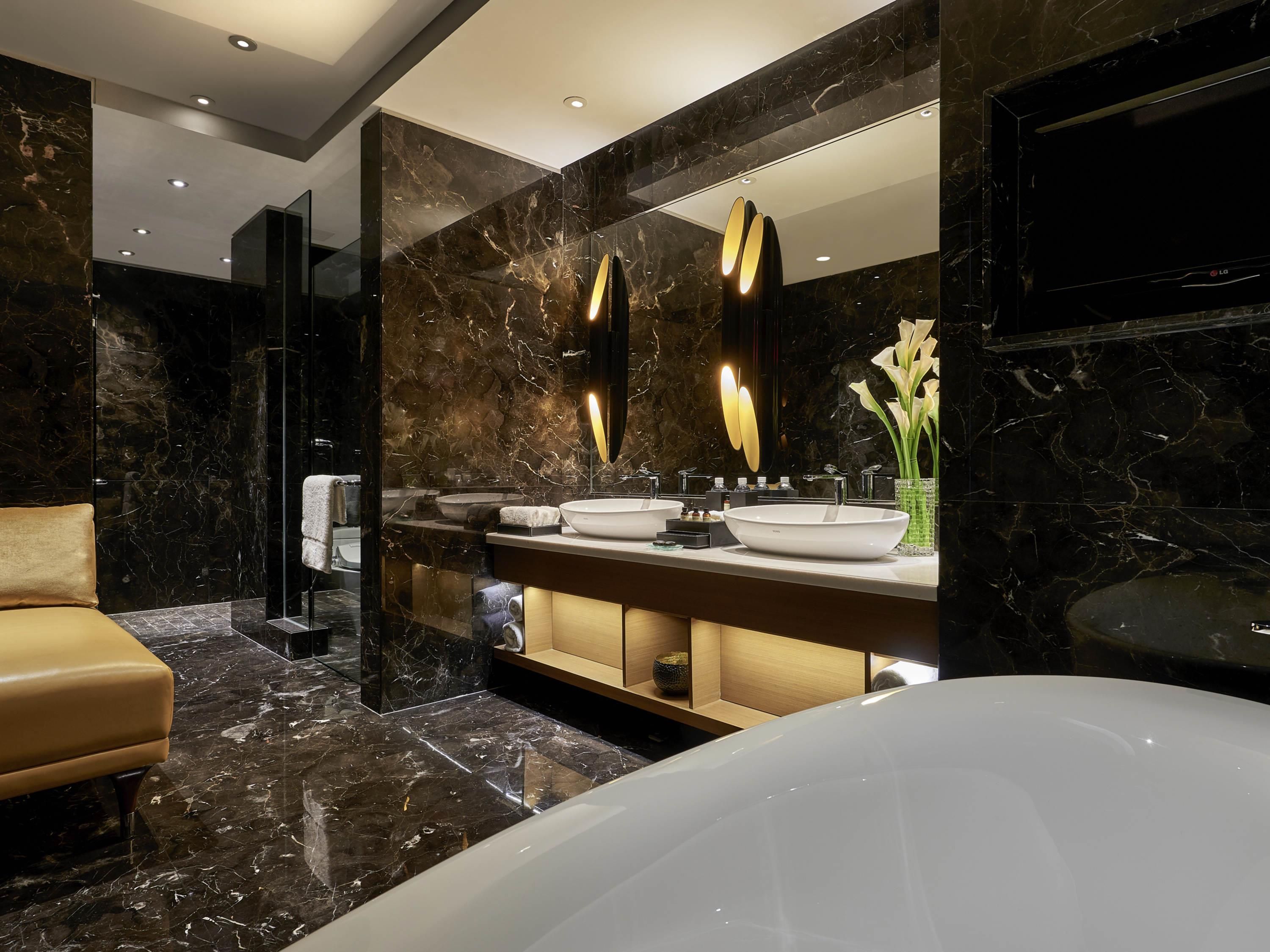 A modern bathroom with a large mirror, two sinks, a bathtub, and marble flooring.
