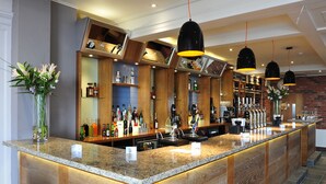 A bar area with a granite countertop, wooden accents, and hanging pendant lights.