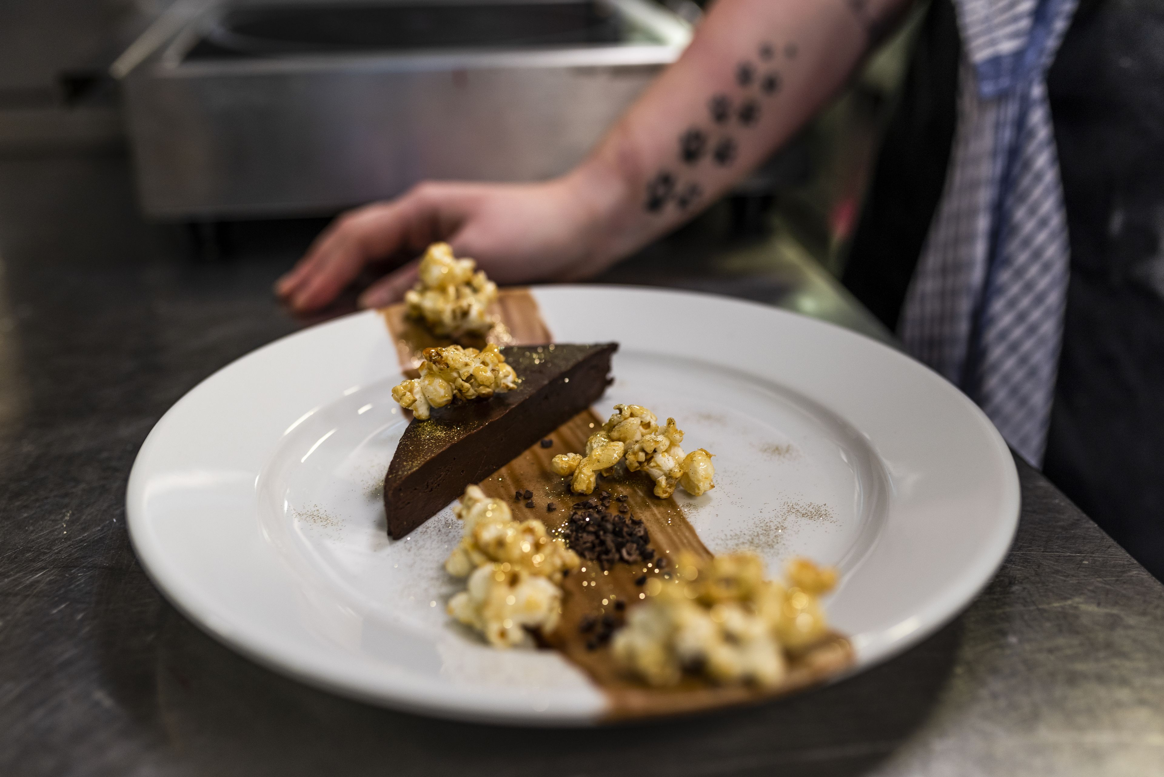 A plate with a dessert consisting of a chocolate piece and caramelized popcorn.