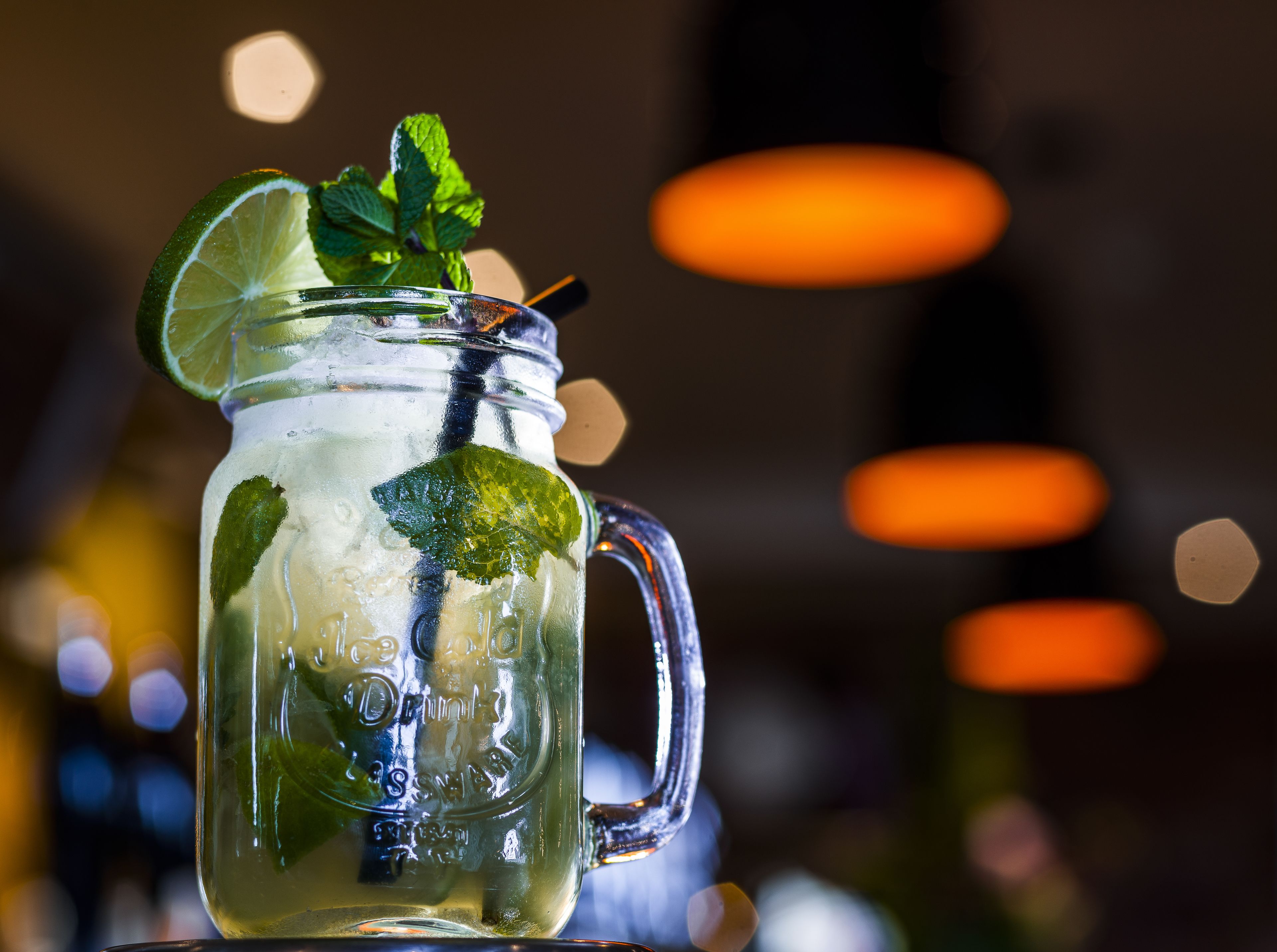 Un vaso de vidrio transparente con hojas de menta y una rodaja de limón, con la etiqueta 'Drinks Less Smart'.