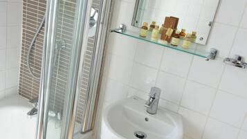 A bathroom with a glass shower enclosure, a white sink, and a mirror above it.