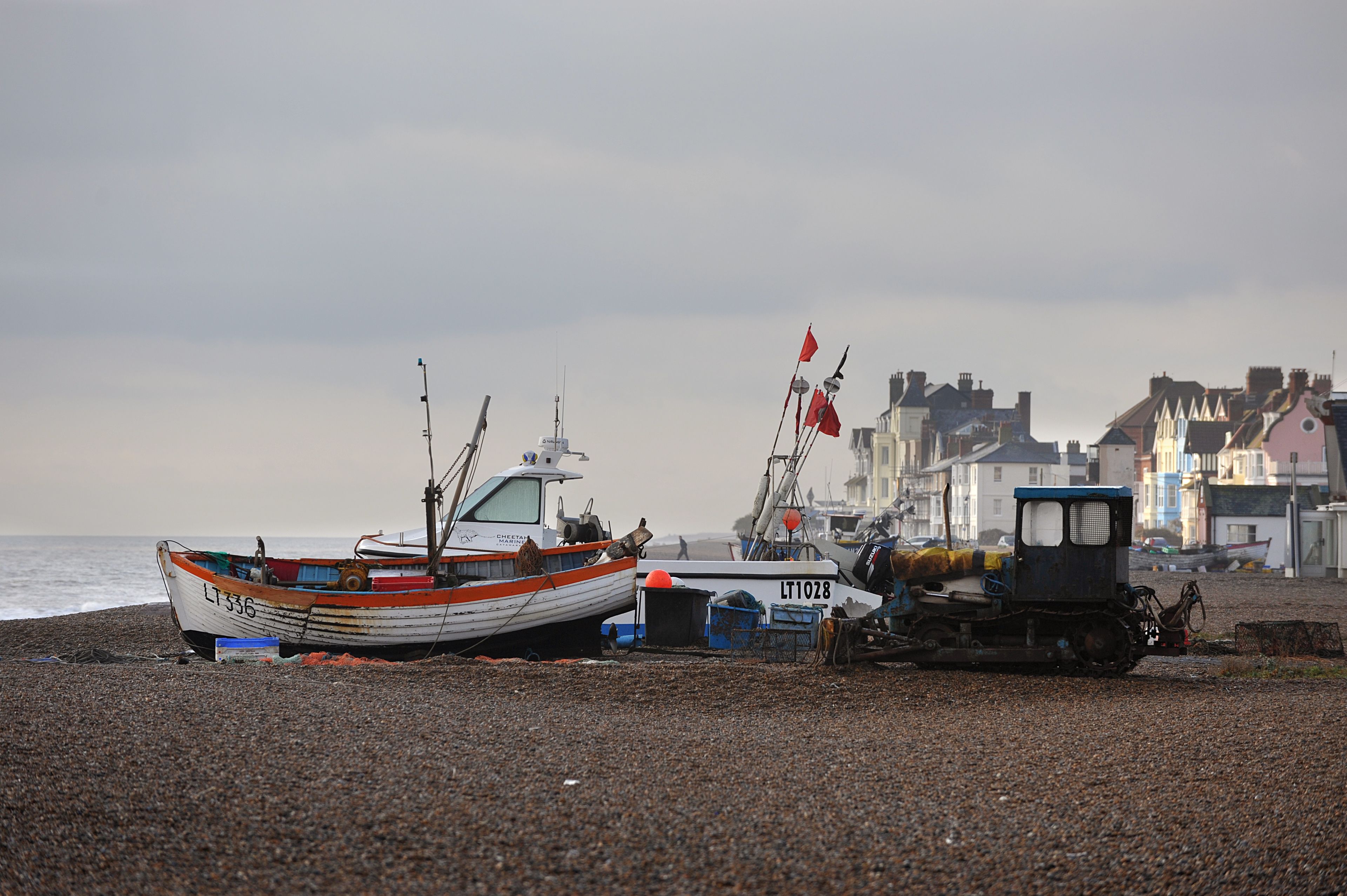 A pebbled beach with boats and a small vehicle.