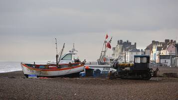 A pebbled beach with boats and a small vehicle.