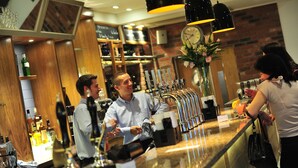 A bar area with multiple taps, a clock, and a vase with flowers.