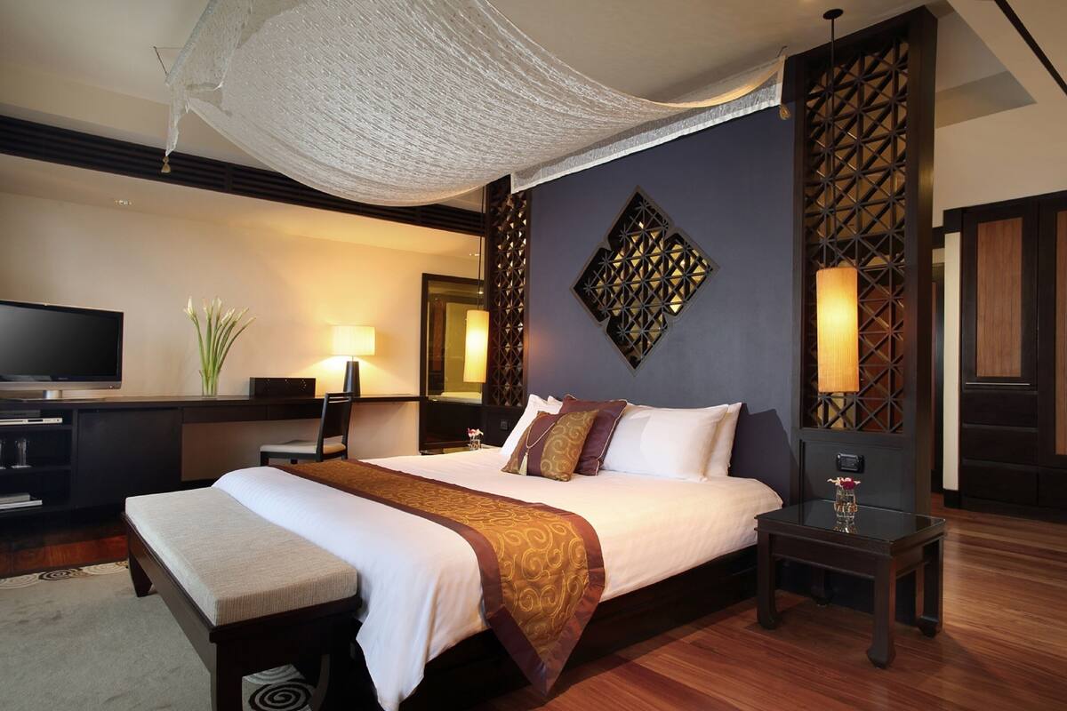 A well-appointed hotel room with a large bed, a television, a desk, and a decorative wall panel.