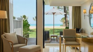 A hotel room with a view of the beach, a glass table, and a seating area with a chair and a small table. - Dusit Thani Laguna Phuket (Choeng Thale)