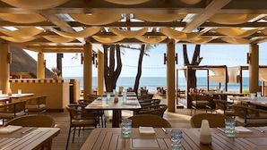 An outdoor dining area with tables and chairs, overlooking the sea. - Dusit Thani Laguna Phuket (Choeng Thale)