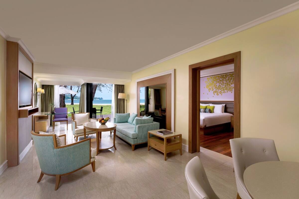 A hotel room with a seating area, a bed, a TV, and a view of the outdoors.