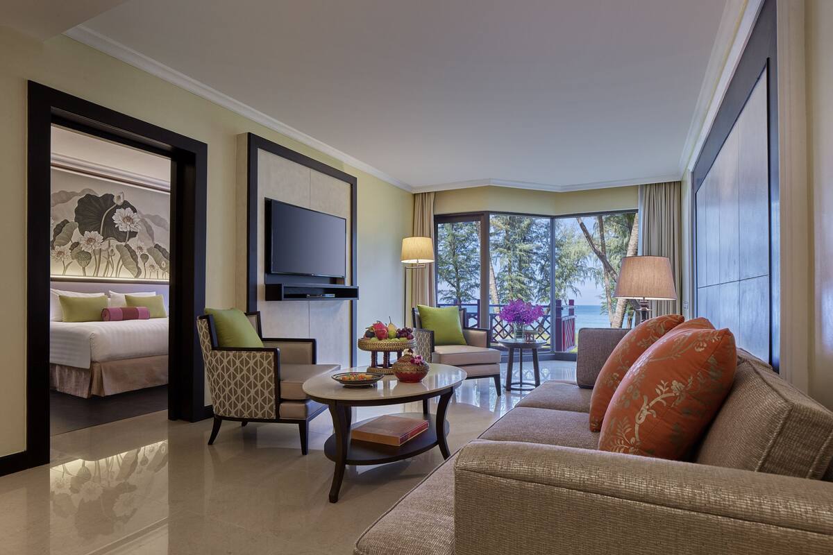 A hotel room with a bed, a TV, a seating area with a table, and a view of the outdoors.