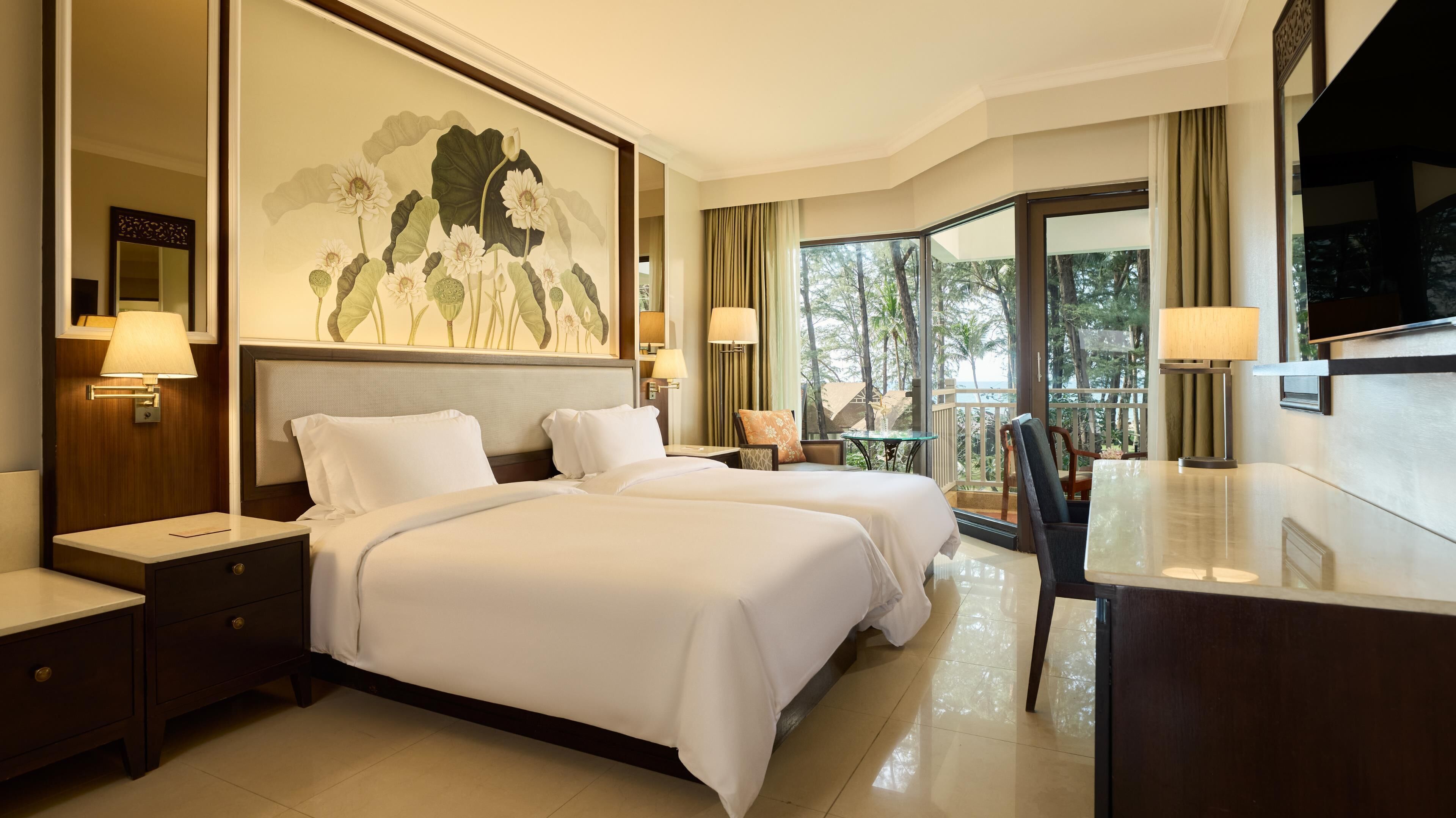 A hotel room with a large bed, a desk, a chair, and a television.