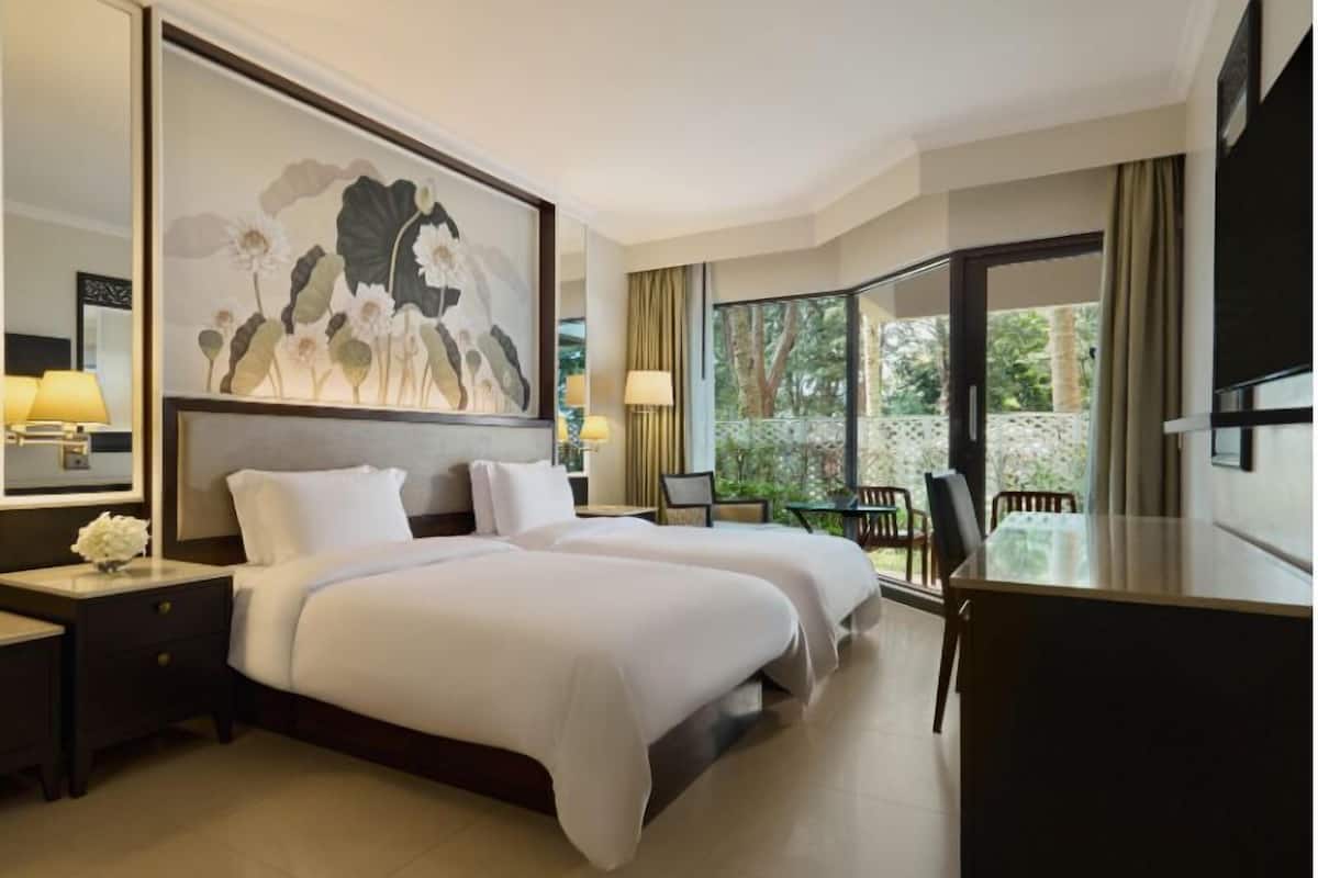 A hotel room with a large bed, a desk, and a view of the outdoors.