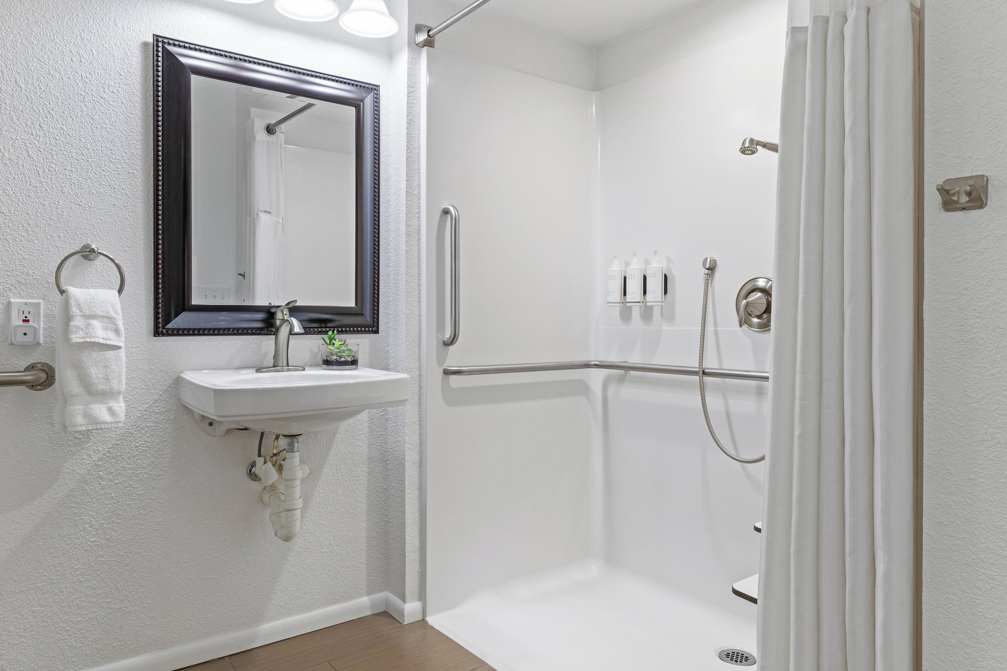 A modern bathroom with a white sink, mirror, and shower.