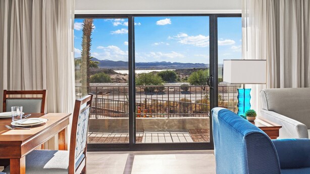 Ein Zimmer mit Esstisch für zwei Personen, einer Couch und einem Balkon mit Landschaftsblick.