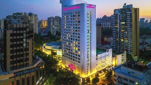 A high-rise hotel with multiple floors, a prominent sign, and surrounding urban buildings. - Crowne Plaza Hotel Shanghai by IHG (Shanghai)