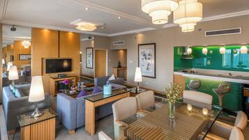 Habitación de hotel moderna con sala de estar, una mesa de comedor y una pared verde decorativa.