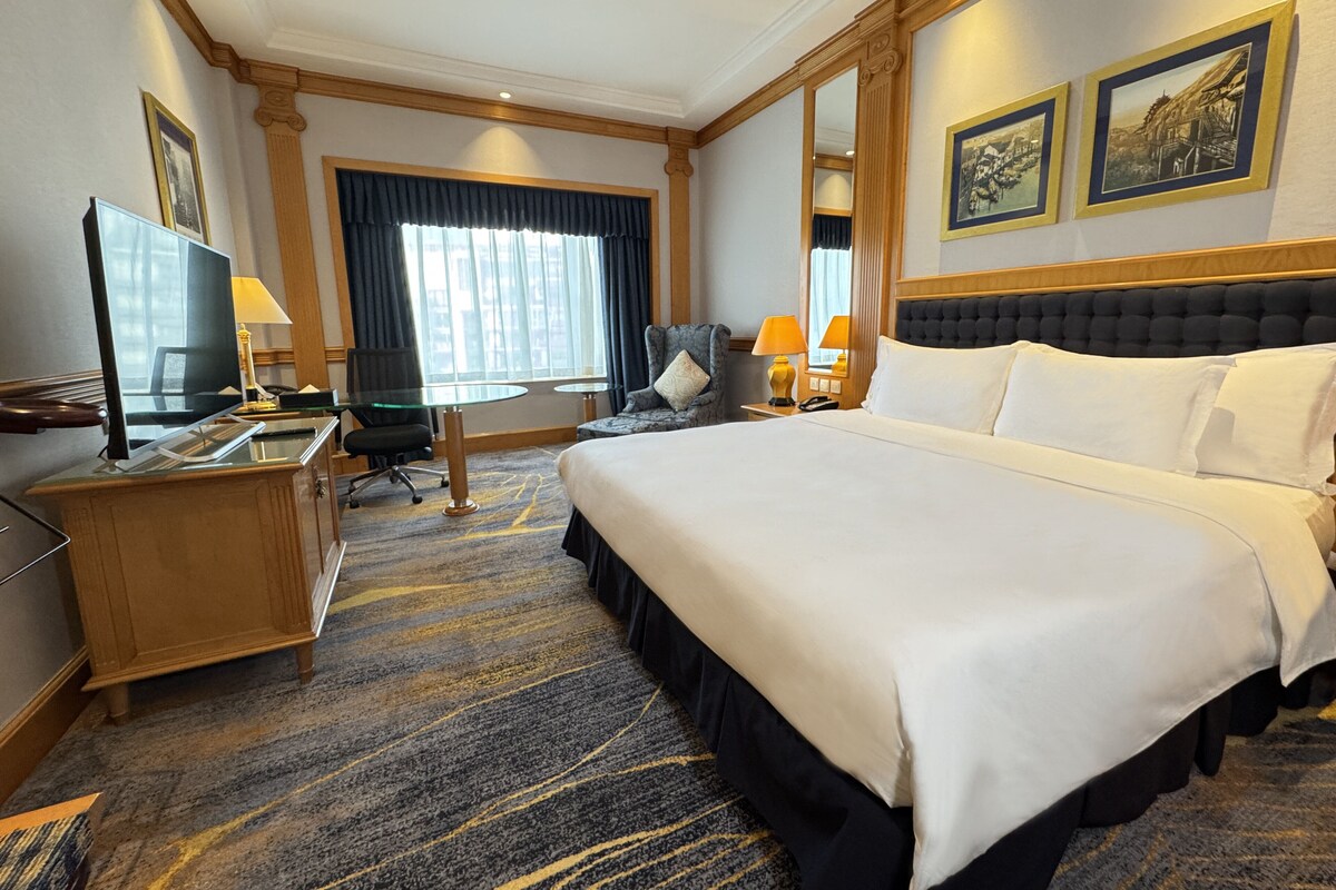 Una habitación de hotel con una cama grande, un escritorio con computadora, una silla y un televisor.