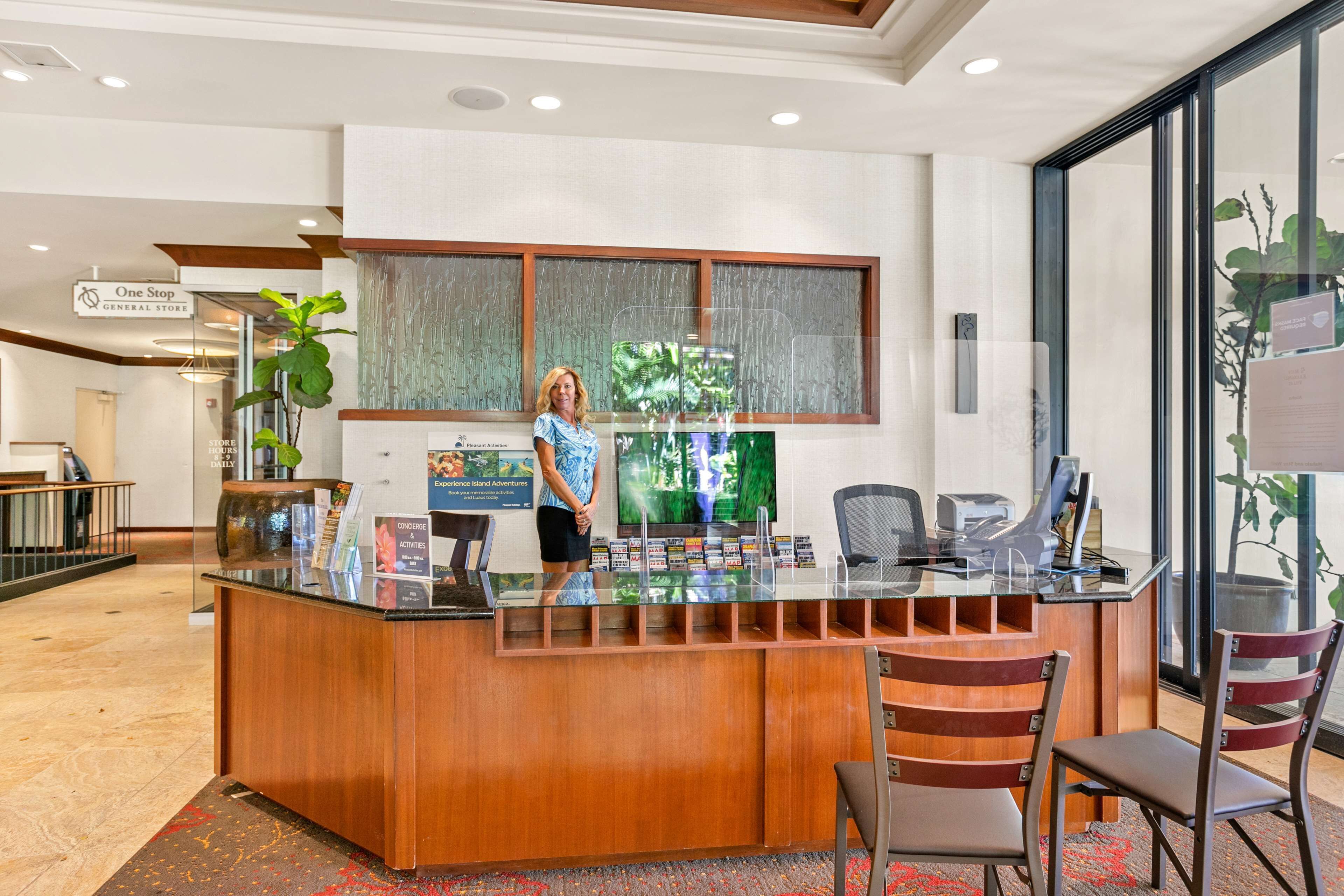 A reception desk with a glass top, wooden paneling, and a large window.