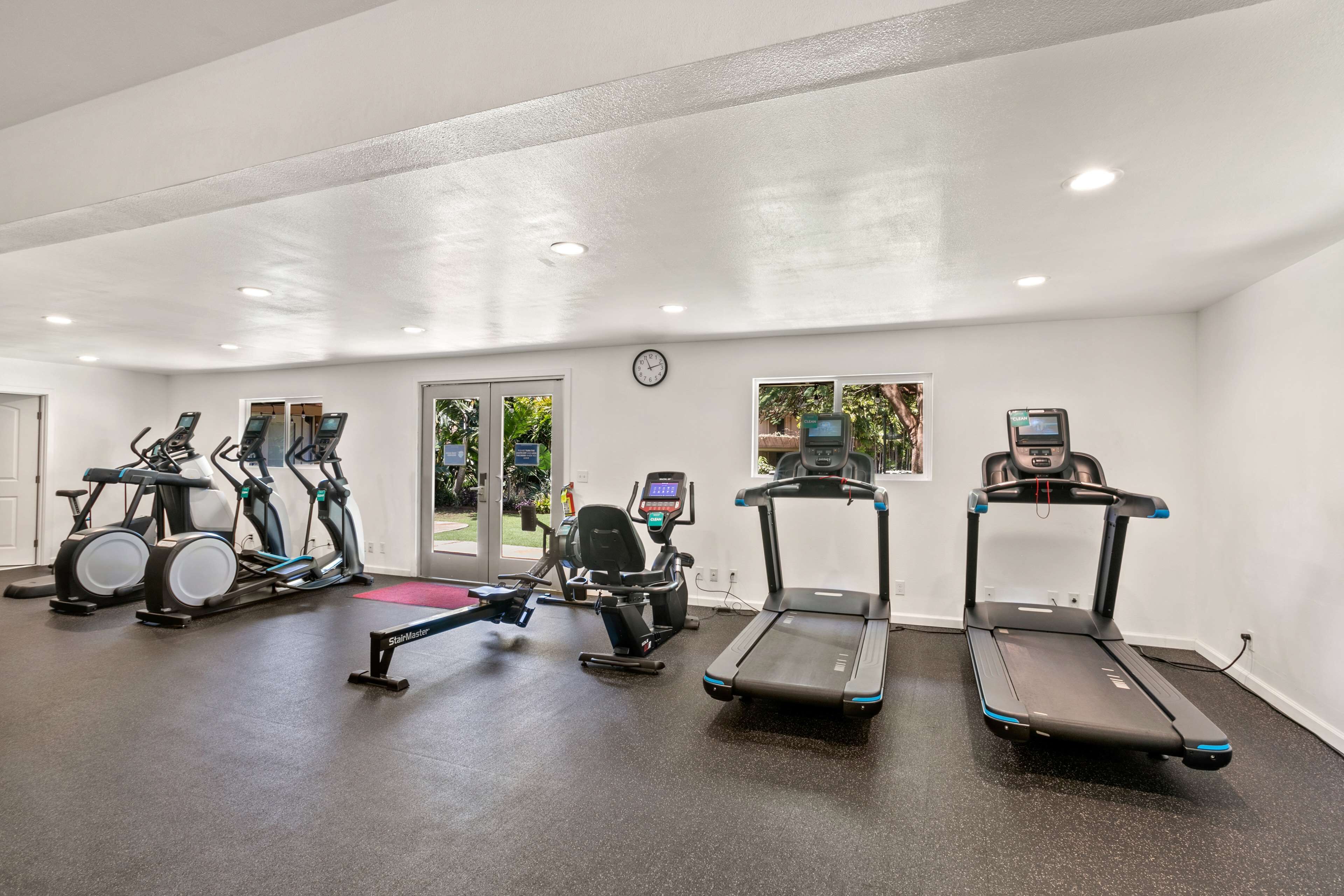 Un gimnasio con cintas de correr, elípticas y una bicicleta estática.